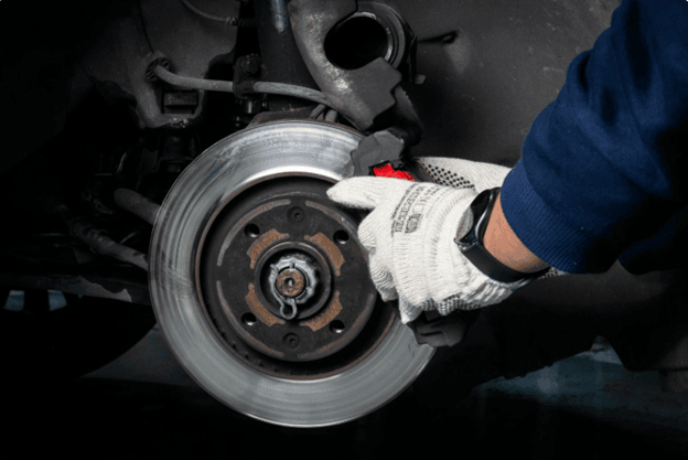 Mechanic inspecting car brake disc and caliper during braking system maintenance